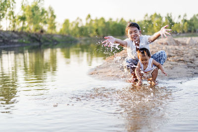 Happy family mother and little daughter playing in the water on the beach on a sunny day.