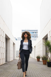 Full length portrait of woman standing against building