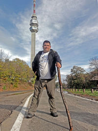 Full length portrait of man standing in city against sky