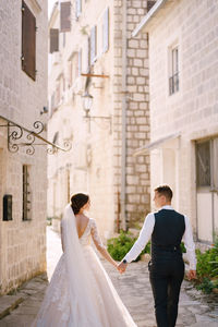 Rear view of couple kissing against building
