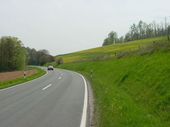 Road amidst green landscape against clear sky