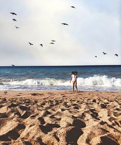 Girl standing on beach against clear blue sky