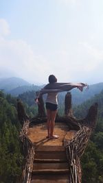 Rear view of woman standing on mountain against sky