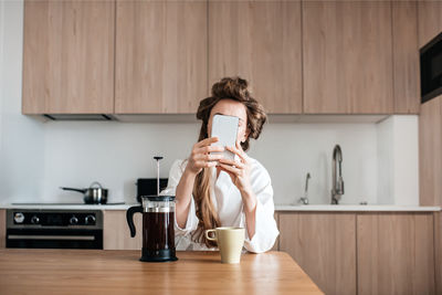 Woman using smart phone in kitchen a home