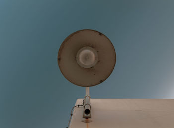 Low angle view of street lamp on white wall against clear blue sky