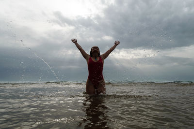 Portrait of smiling young woman in sea against sky