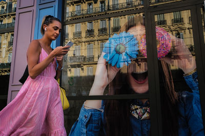 Young woman holding umbrella standing with reflection in mirror