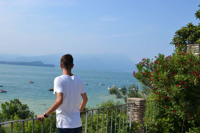 Rear view of man standing on mountain against sky