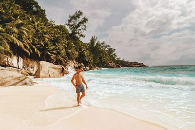 Rear view of man on beach against sky