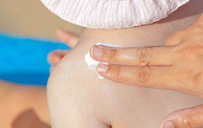 Woman applying sunscreen on daughter skin at beach