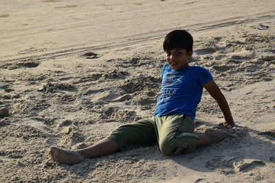 Portrait of boy sitting on sand at beach