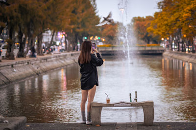 Rear view of woman standing by lake and a bird