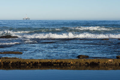 Seashore tidal pool and rocks with offshore drilling platform