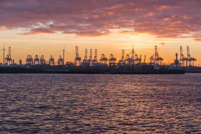 Silhouette of cranes at harbor during sunset