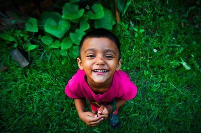 Portrait of smiling boy standing on grassy field