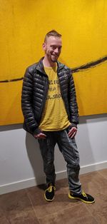 Full length portrait of man standing against yellow wall