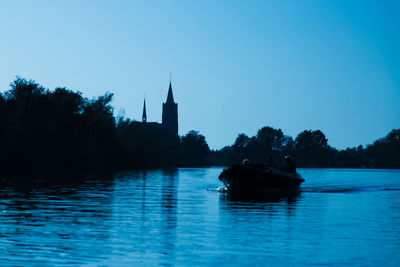 Boat sailing in river against clear blue sky