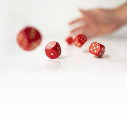 Close-up of hand on red table against white background