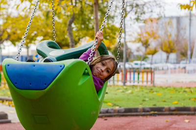 Close-up of girl on swing in playground