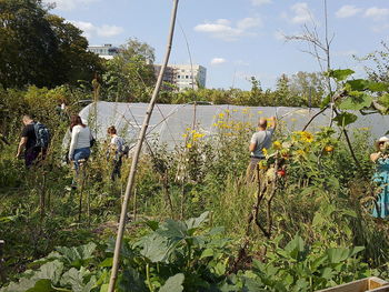 People by plants against trees and sky