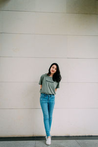 Portrait of woman standing against wall