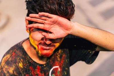 Close-up portrait of man covered with powder paint in sunny day