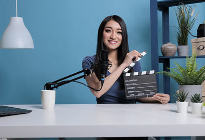 Portrait of smiling blogger holding film slate