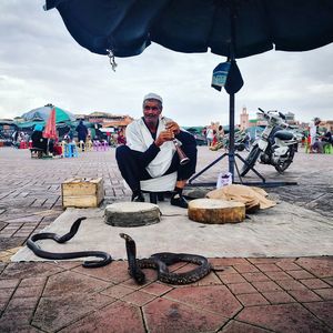 Snake charmer sitting with snakes on footpath