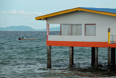 Stilt house in sea against sky