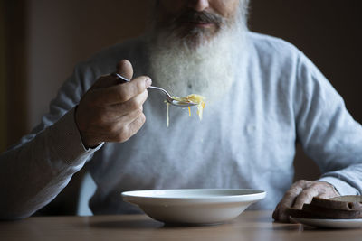 Midsection of man eating food on table