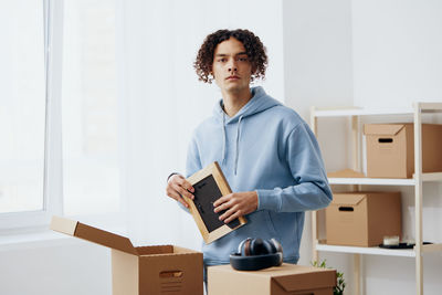 Portrait of young man putting things in cardboard box