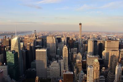 Aerial view of buildings in city against cloudy sky