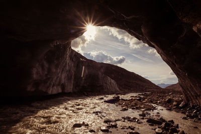 Glacial stream that coming out of a cave carved into a glacier ice at sunset