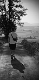 Rear view of man walking on road