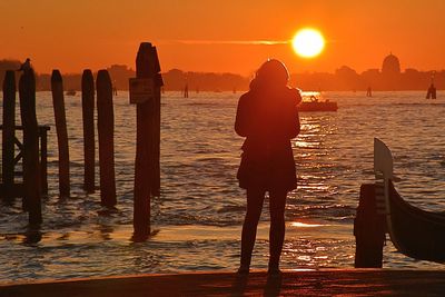 Silhouette woman standing on beach during sunset