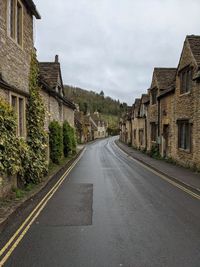 Empty road by buildings in city against sky in english countryside in the cotsworlds 