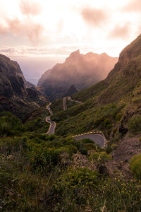 Picturesque view of serpentine asphalt road going through rocky mountains covered with green plants in morning in tenerife