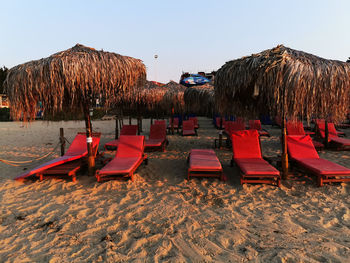 Lounge chairs on beach against clear sky