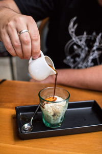 Midsection of person pouring drink in glass