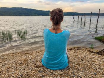 Rear view of woman standing at beach against sky