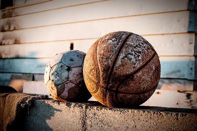 Close-up of damaged soccer and basketball on retaining wall