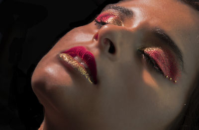 Close-up of woman wearing make-up against black background