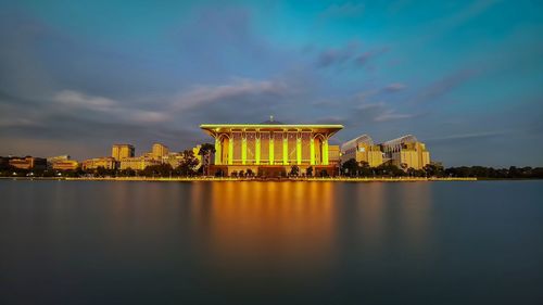 View of building by lake against sky in city