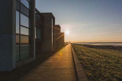 Footpath amidst sea against sky during sunset