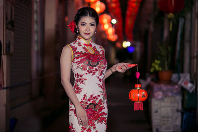 Portrait of young woman wearing cheongsam during festival at night