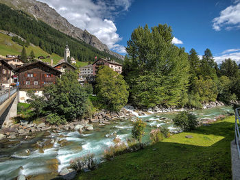 Scenic view of river amidst trees and buildings against sky