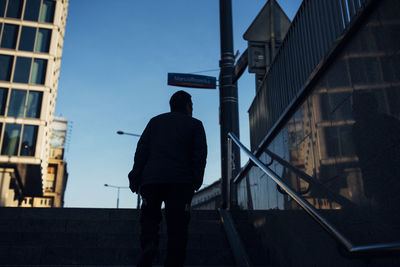 Rear view of man standing by railing in city