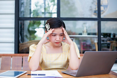 Young woman using mobile phone while sitting on table