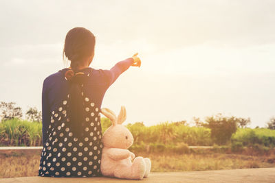 Rear view of woman with toy against sky