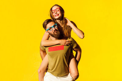 Full length of woman standing against yellow background